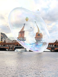 Digital composite image of bubbles and river against sky