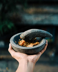 Cropped hand holding food in mortar and pestle 