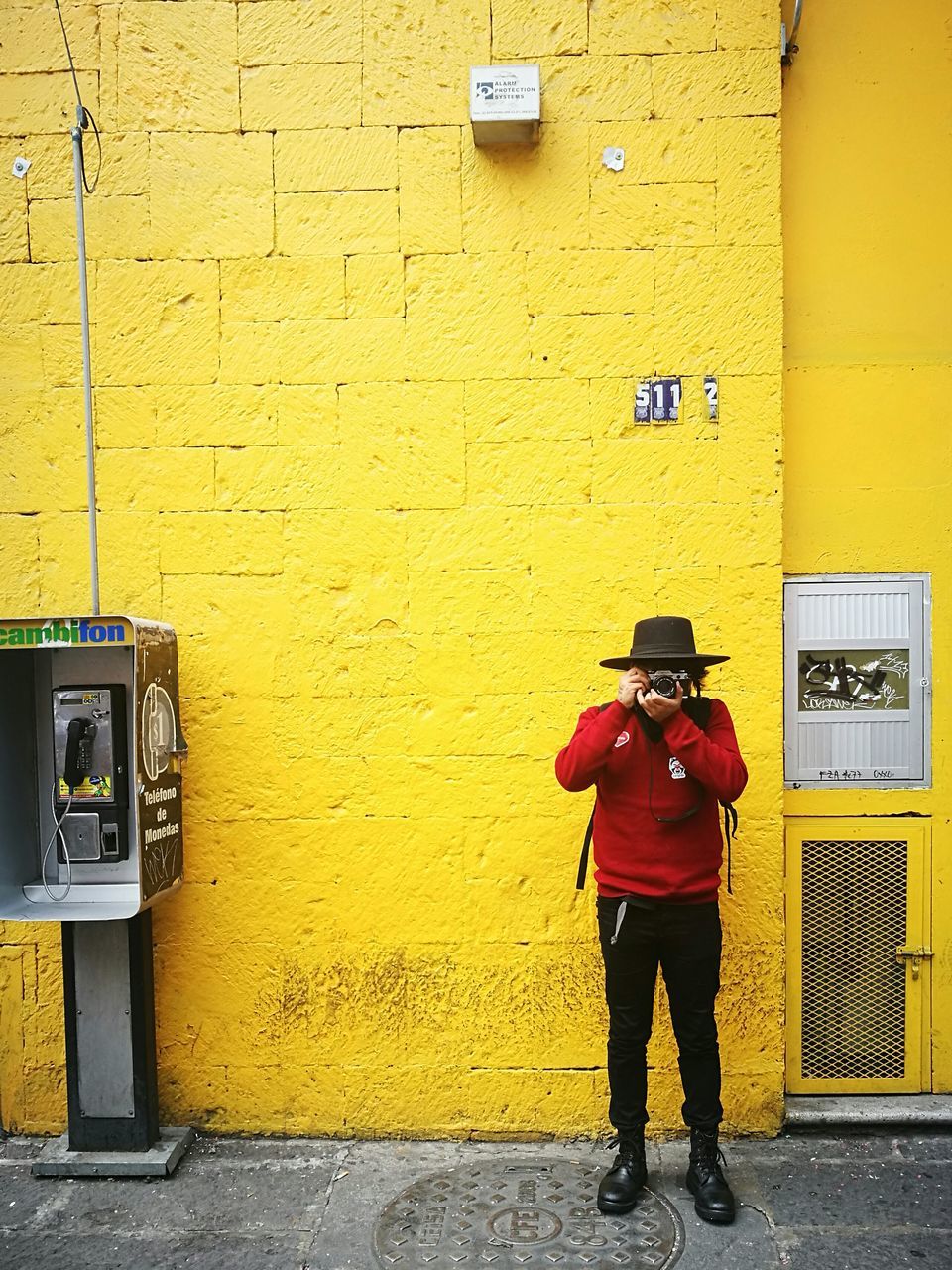 yellow, communication, architecture, built structure, technology, standing, building exterior, wireless technology, pay phone, day, one person, full length, outdoors, people