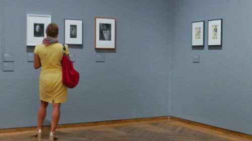 Rear view of man standing against wall at museum