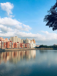 Buildings by river against sky in city