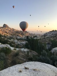 Hot air balloon flying over rocks against sky