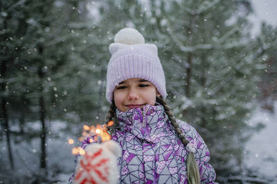 Smiling girl holding sparkler during winter