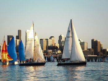 Sailboats in sea with city in background