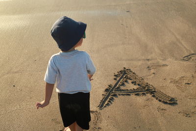 Rear view of boy standing at beach