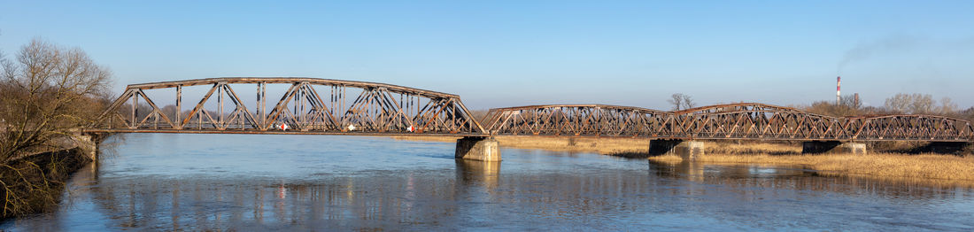 Bridge over river against clear blue sky