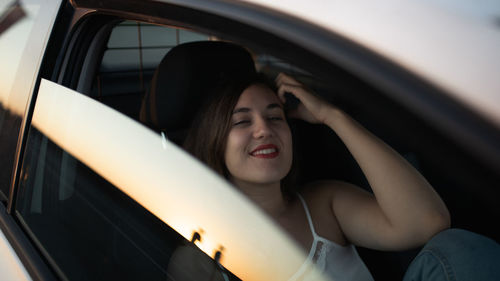 Portrait of smiling woman in car from its window