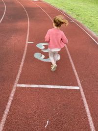 Rear view of boy running on the road