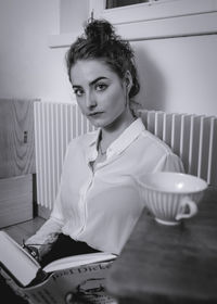 Portrait of woman sitting on table at home