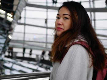 Portrait of beautiful woman standing against railing