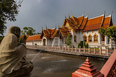 Rear view of man standing by building against sky