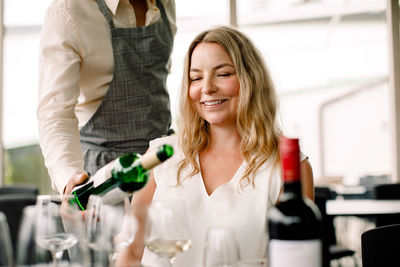 Businessman serving wine to smiling female colleague at convention center