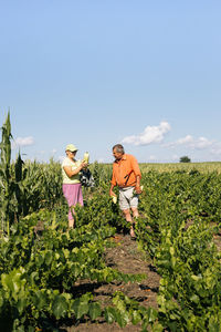 People standing by plants on landscape against sky