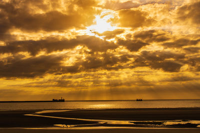 Scenic view of sea against dramatic sky during sunset