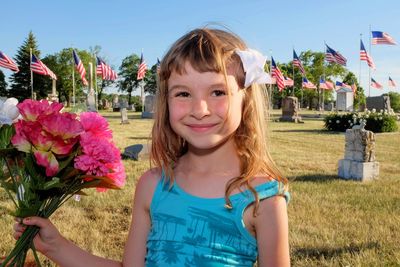 Girl with artificial flowers standing on field