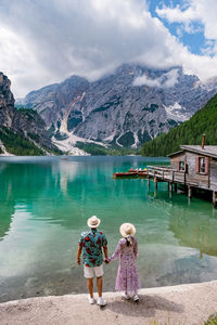 Rear view of women standing by lake against mountains