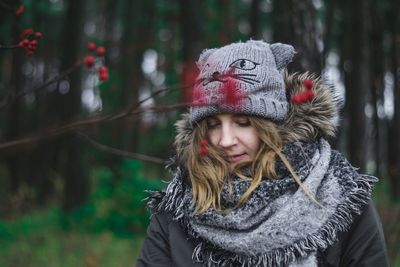 Portrait of smiling young woman in forest during winter