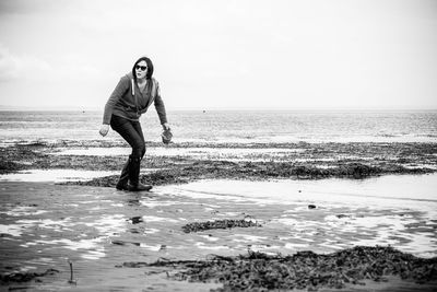 Full length of woman standing on shore at beach against sky