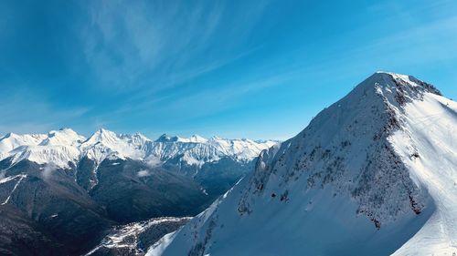 Panoramic view of snowcapped mountains against blue sky