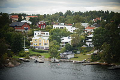 Houses by river amidst buildings against sky