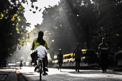 Rear view of man riding bicycle on road in city