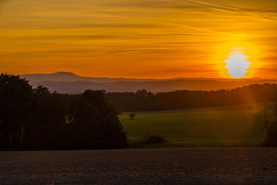 Scenic view of field against orange sky