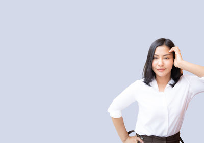 Beautiful young woman standing against white background