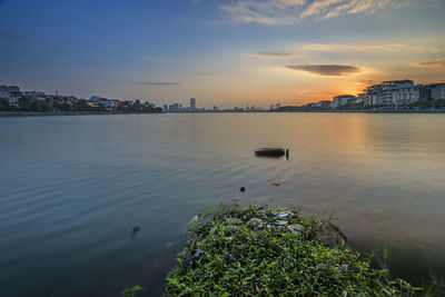 Scenic view of sea and buildings against sky during sunset