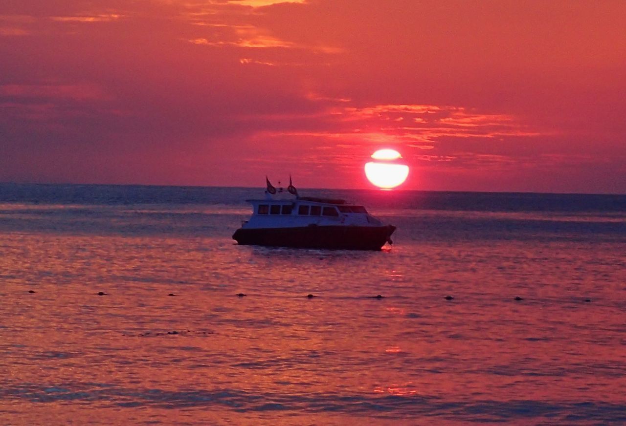 BOAT SAILING IN SEA AGAINST ORANGE SKY