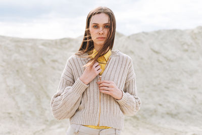 Fashion beauty portrait of woman in knitted cardigan on desert background, autumn outfit