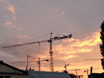 Low angle view of silhouette cranes against sky