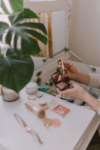 Cropped hands of woman holding beauty products on table at home