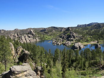 Scenic view of lake and rocks against clear blue sky