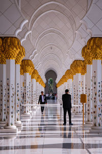 Rear view of people walking in corridor of building