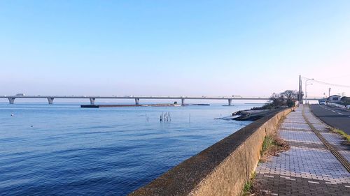 Bridge over calm sea against clear sky