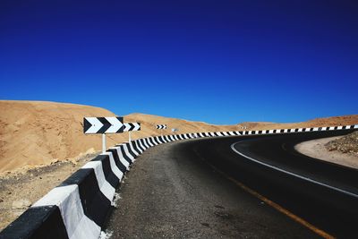 Zebra crossing on road against clear blue sky