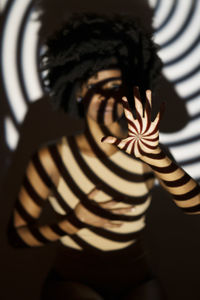 Spiral pattern shadow on woman in front of wall