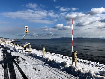 Road by sea against sky during winter