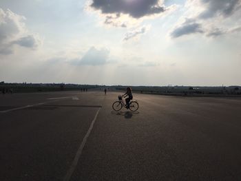 People on road against cloudy sky