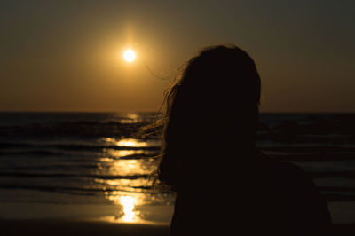 Silhouette woman at beach against sky during sunset