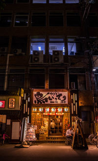 Low angle view of illuminated shop at night