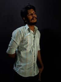 Young man looking away against black background