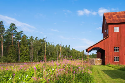 Scenic view of flowering plants and trees on field against sky