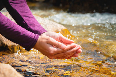 Female hands, palms that are filled with mountain spring water on a sunny day, close-up