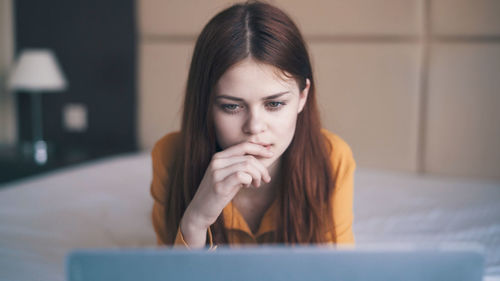 Portrait of young woman sitting on bed at home