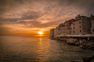 Buildings by sea during sunset