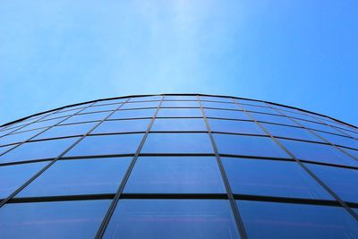 Low angle view of glass building against blue sky