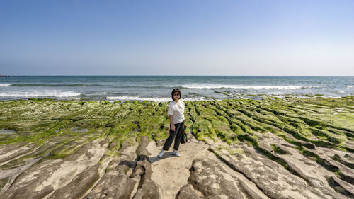 Rear view of woman walking at beach against clear sky