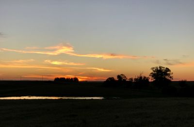 Scenic view of silhouette field against sky during sunset