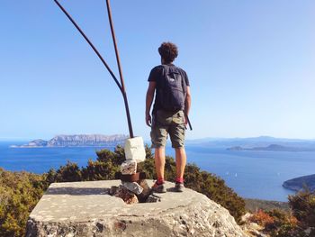 Rear view of man looking at sea against sky
